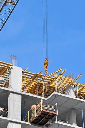 Crane and building construction site against blue skyの写真素材