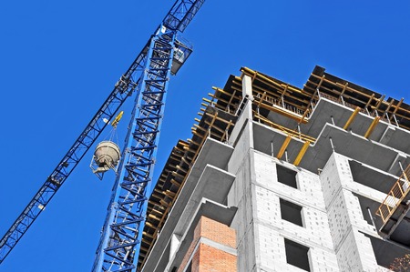 Crane lifting concrete mixer container against blue skyの写真素材