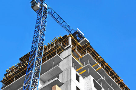 Crane and building construction site against blue sky