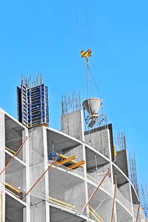 Crane lifting concrete mixer container against blue skyの写真素材