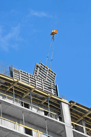 Crane hoisting formwork over construction site work