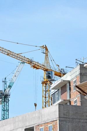 Crane and building construction site against blue skyの写真素材