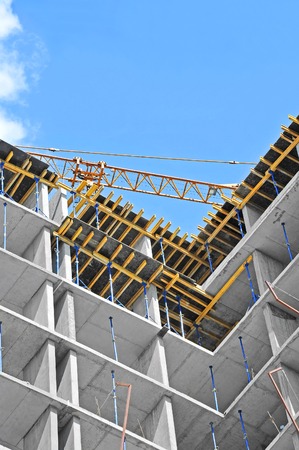 Crane and building construction site against blue skyの写真素材