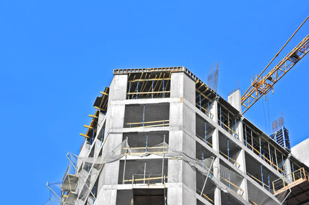 Crane and building construction site against blue sky