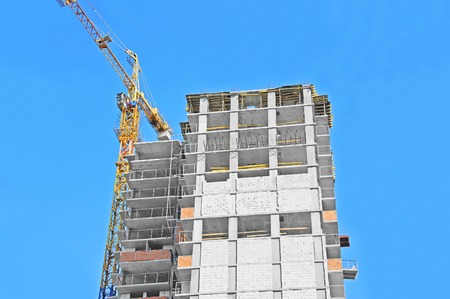 Crane and building construction site against blue skyの写真素材