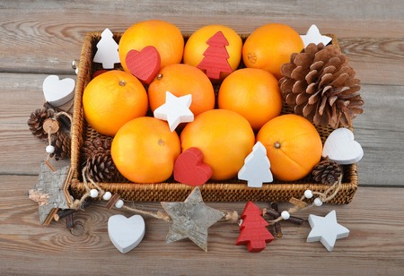 Orange in wickered tray on wooden background with Christmas decorの写真素材