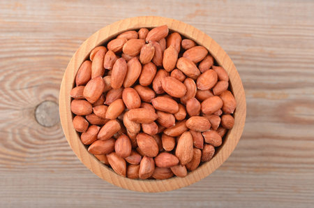 Groundnuts in wooden bowl on board background