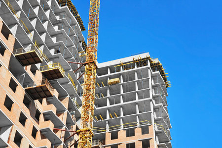 Building crane and building under construction against blue sky