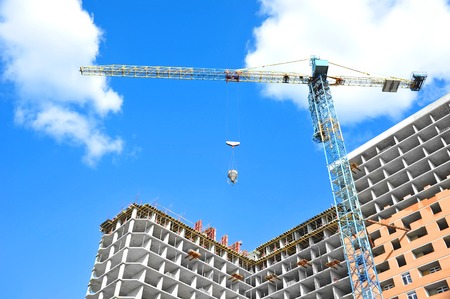 Crane lifting concrete mixer container against blue skyの写真素材