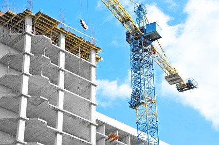 Building crane and building under construction against blue skyの写真素材