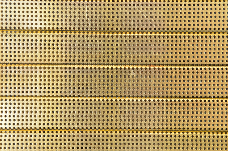 Perforated textured yellow metallic background, close upの写真素材