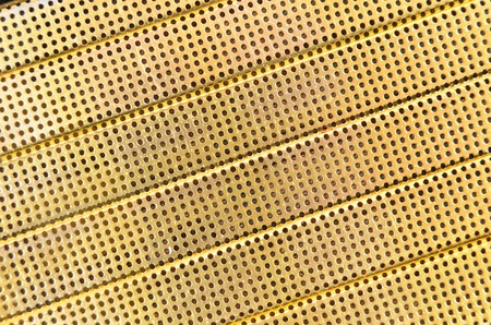 Perforated textured yellow metallic background, close upの写真素材