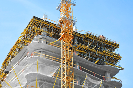 Crane and building under construction against blue skyの写真素材