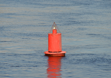 Red river buoy floating on the waveの写真素材