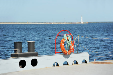 Red lifebuoy and bollard on metal pier