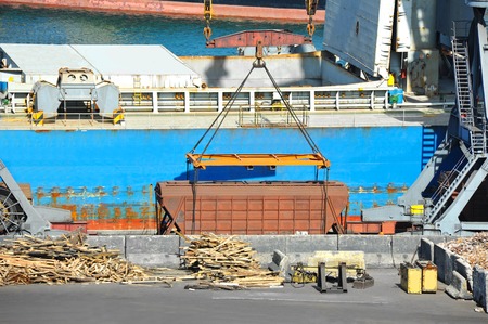 Bulk cargo ship and train under port crane bridgeの写真素材
