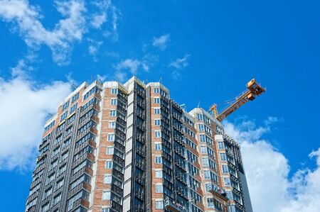 Crane and building under construction against blue skyの写真素材