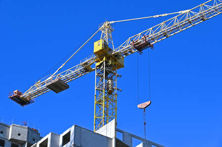 Crane and building under construction against blue skyの写真素材
