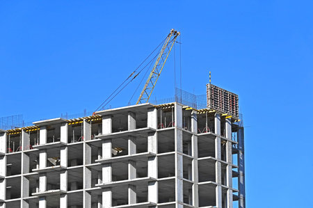 Crane and building under construction against blue sky