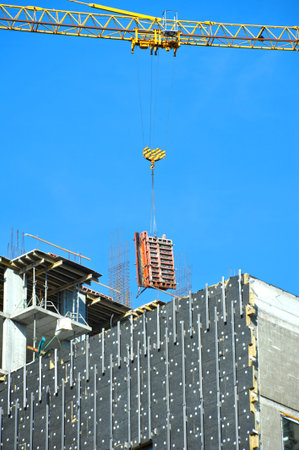 Crane and building under construction against blue sky