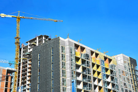 Crane and building under construction against blue sky