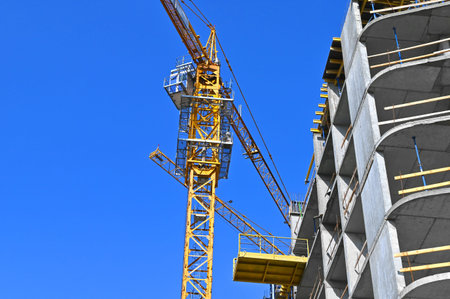 Crane and building under construction against blue sky
