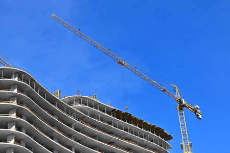 Crane and building under construction against blue sky