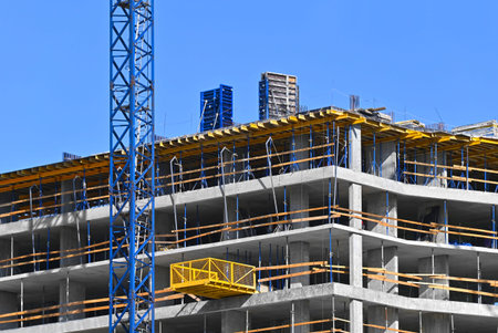 Crane and building under construction against blue sky