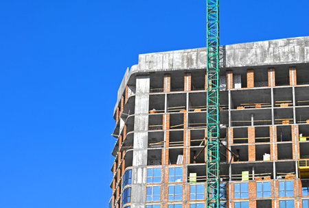 Crane and building under construction against blue sky