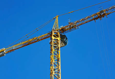 Tall construction tower crane against blue skyの写真素材
