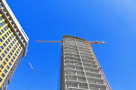 Crane and building under construction against blue skyの写真素材