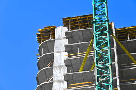 Crane and building under construction against blue skyの写真素材