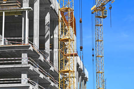 Crane and building under construction against blue skyの写真素材