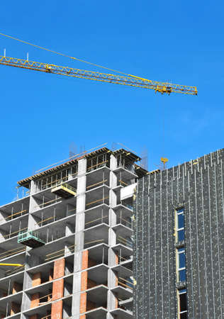 Crane and building under construction against blue skyの写真素材