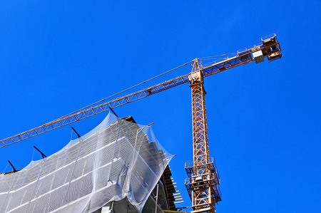 Crane and building under construction against blue sky