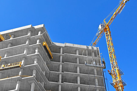 Crane and building under construction against blue sky