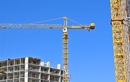Crane and building under construction against blue sky