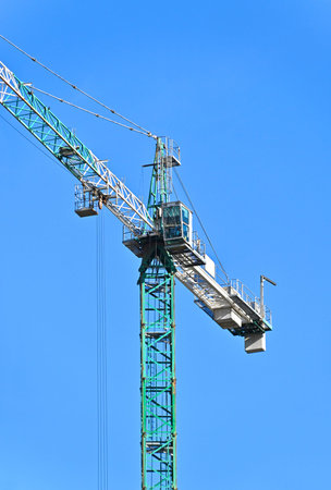 Tall construction tower crane against blue sky