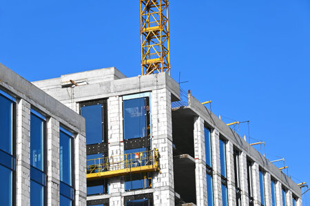 Crane and building under construction against blue sky