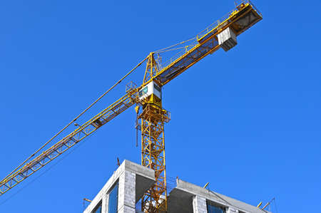 Crane and building under construction against blue skyの写真素材