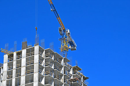 Crane and building under construction against blue sky