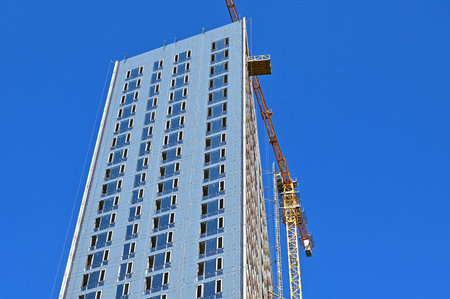 Crane and building under construction against blue sky
