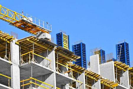 Crane and building under construction against blue sky