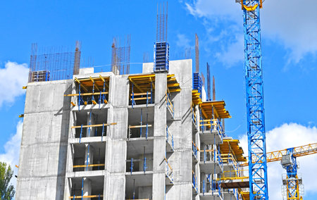 Crane and building under construction against blue sky