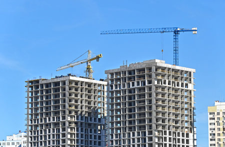 Crane and building under construction against blue sky