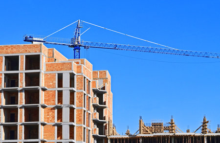 Highrise construction site with crane and blue skyの写真素材