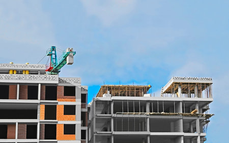 Crane at construction site against cloudy sky