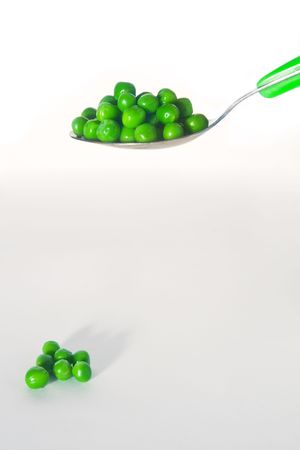 Fresh green peas on a silver spoon, isolated on white backgroundの写真素材