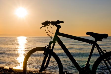 silhouette of a bike on the beach at sunsetの写真素材