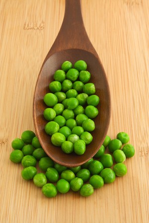 Fresh green peas on a wooden spoonの写真素材